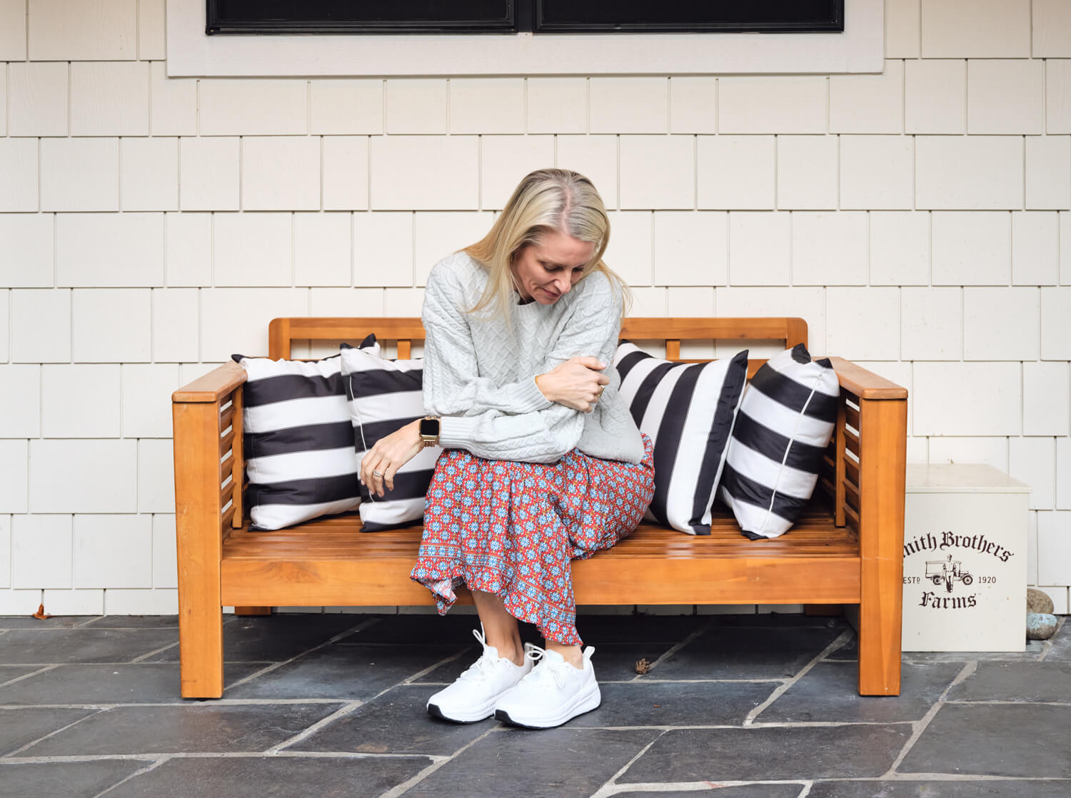 Older women wearing hands-free shoes while sitting down on a bench.