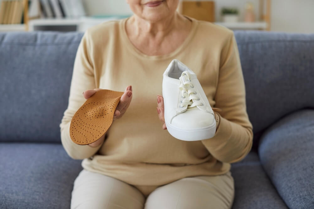 Woman showing removable insole from sneaker.
